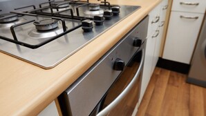 Una cocina con estufa, horno de acero inoxidable y encimera de madera.