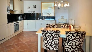 Une cuisine moderne avec des meubles blancs, un plan de travail noir et un coin repas doté de chaises à motifs.