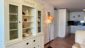 Une cuisine avec des meubles blancs, un coin repas avec une chaise et un lampadaire.