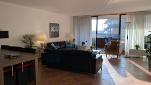 Uma sala de estar moderna com sofá, mesa de jantar e varanda com vista.