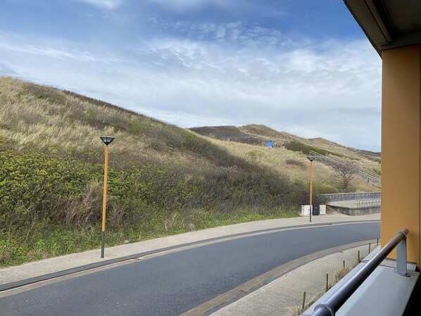 A road curving through a hilly landscape with street lamps and a guardrail.