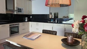 Una cucina moderna con zona pranzo, caratterizzata da un'isola grande, un forno a microonde e una macchina da caffè.