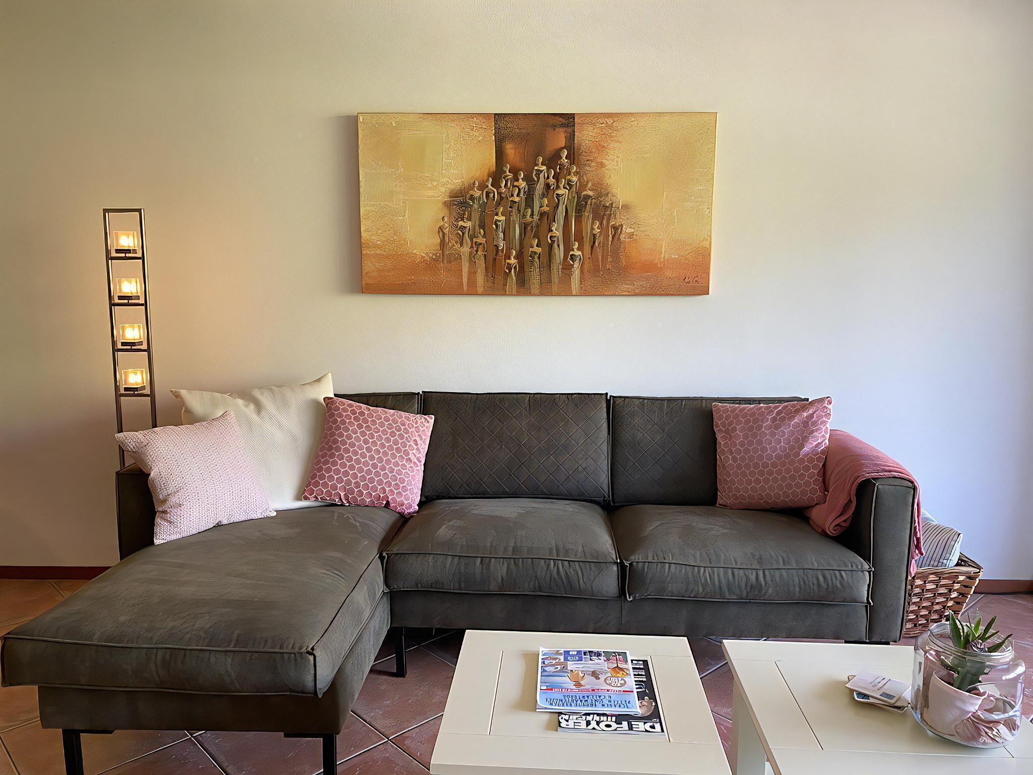 Uma sala de estar moderna com um sofá seccional, uma mesa de centro e uma obra de arte na parede.