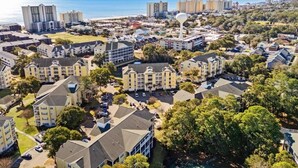 Un barrio residencial con edificios de apartamentos y casas, una torre de agua destacada y vista al océano.
