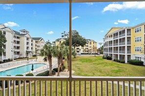 Vista de un conjunto residencial con varios balcones, una piscina y céspedes bien cuidados.