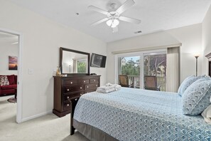 Un dormitorio con cama, cómoda y ventilador de techo.