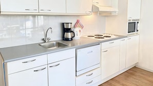 A modern kitchen with white cabinets, a stainless steel sink, a coffee maker, and a microwave.