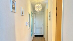 A hallway with a wooden floor, white walls, and a door at the end.
