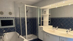 Une salle de bain moderne avec une baignoire sur pieds, une douche à parois de verre et un meuble-lavabo doté de deux vasques.