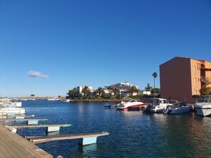 A marina with boats docked, a clear sky, and buildings in the background. - T2 Apartment at the Marina (Saint-Cyprien)