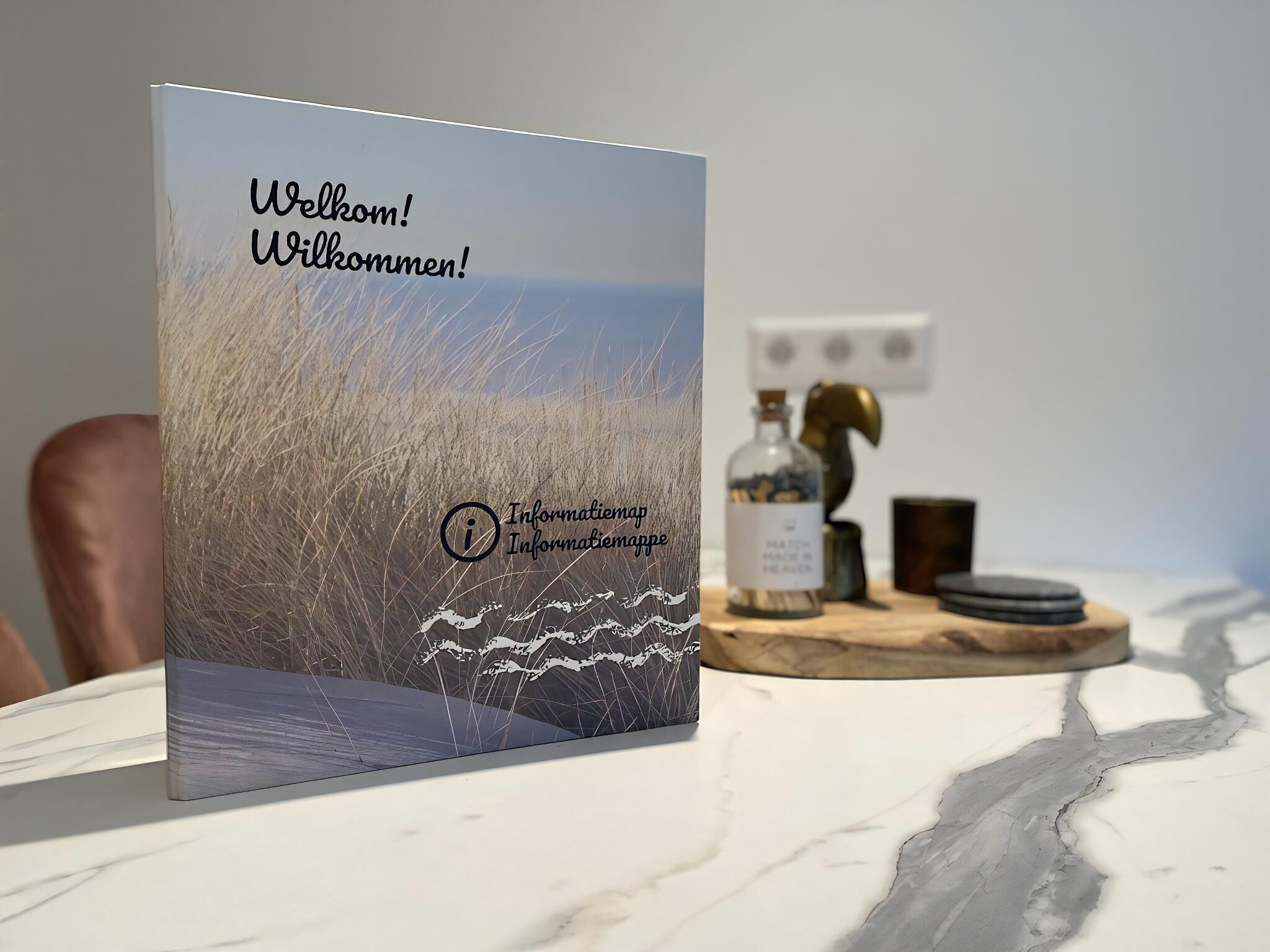 A welcome sign with a scenic background, a bottle, and a cup on a table.