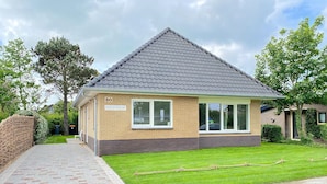 A single-story house with a grey tiled roof, a brick base, and a number '30' on the front.