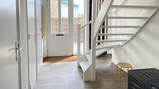 A modern interior with a staircase, a door leading outside, and a small table.
