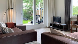 A modern living room with a sofa, a TV, and a dining area.