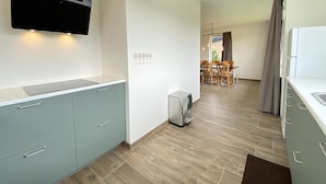 A modern kitchen with grey cabinets, a built-in microwave, and a small trash bin.