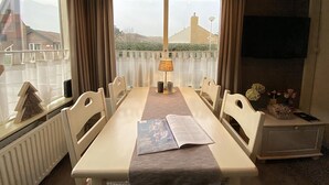 A dining area with a table, chairs, a lamp, and a magazine. - 2 bedroom accommodation in Callantsoog (Callantsoog)