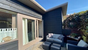 A modern patio with a sliding glass door, wicker furniture, and a small table. - 2 bedroom accommodation in Callantsoog (Callantsoog)