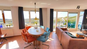 A modern hotel room with a dining area, a sofa, and large windows offering a view of the countryside. - 3 bedroom accommodation in Callantsoog (Callantsoog)