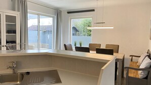 A modern kitchen with a large island, a built-in sink, and a dining area with a table and chairs. - 2 bedroom accommodation in Callantsoog (Callantsoog)