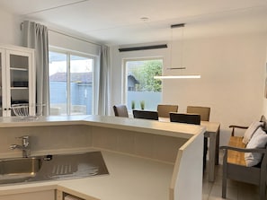 A modern kitchen with a large island, a built-in sink, and a dining area with a table and chairs.