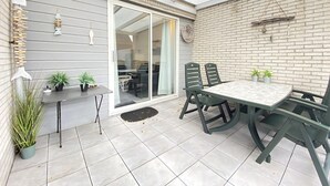 A patio with a table and chairs, potted plants, and a sliding glass door leading to an indoor area. - 2 bedroom accommodation in Callantsoog (Callantsoog)