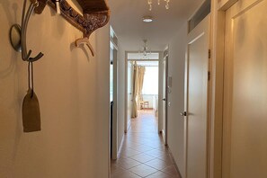 A narrow hallway with a tiled floor, a chandelier, and a door on the right. - Callantsoger Staete A03 (Callantsoog)