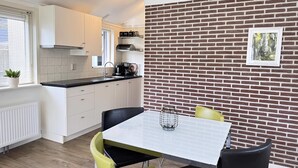 Een moderne keuken met witte kasten, een zwart aanrecht en een bakstenen muur met een ingelijste foto.