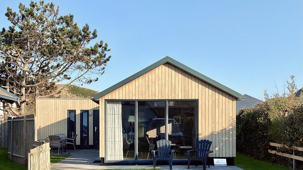 Een modern houten gebouw met een grote glazen deur en schuiframen naar het terras.