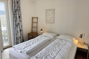 A bedroom with a bed, a nightstand, a lamp, a window with curtains, and a wall-mounted bird illustration. - 2 bedroom accommodation in Callantsoog (Callantsoog)