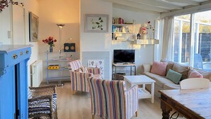 A cozy living room with a TV, striped chairs, a sofa, and a bookshelf. - 3 bedroom accommodation in Callantsoog (Callantsoog)