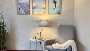 A room with a grey armchair, a small side table with a lamp, and three framed pictures on the wall. - Callantsoger Staete A08 (Callantsoog)