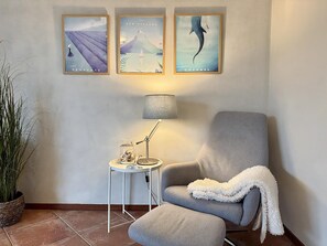 A room with a grey armchair, a small side table with a lamp, and three framed pictures on the wall. - Callantsoger Staete A08 (Callantsoog)