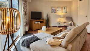 A modern living room with a sofa, a television, a lamp, and a decorative lamp. - Callantsoger Staete A08 (Callantsoog)