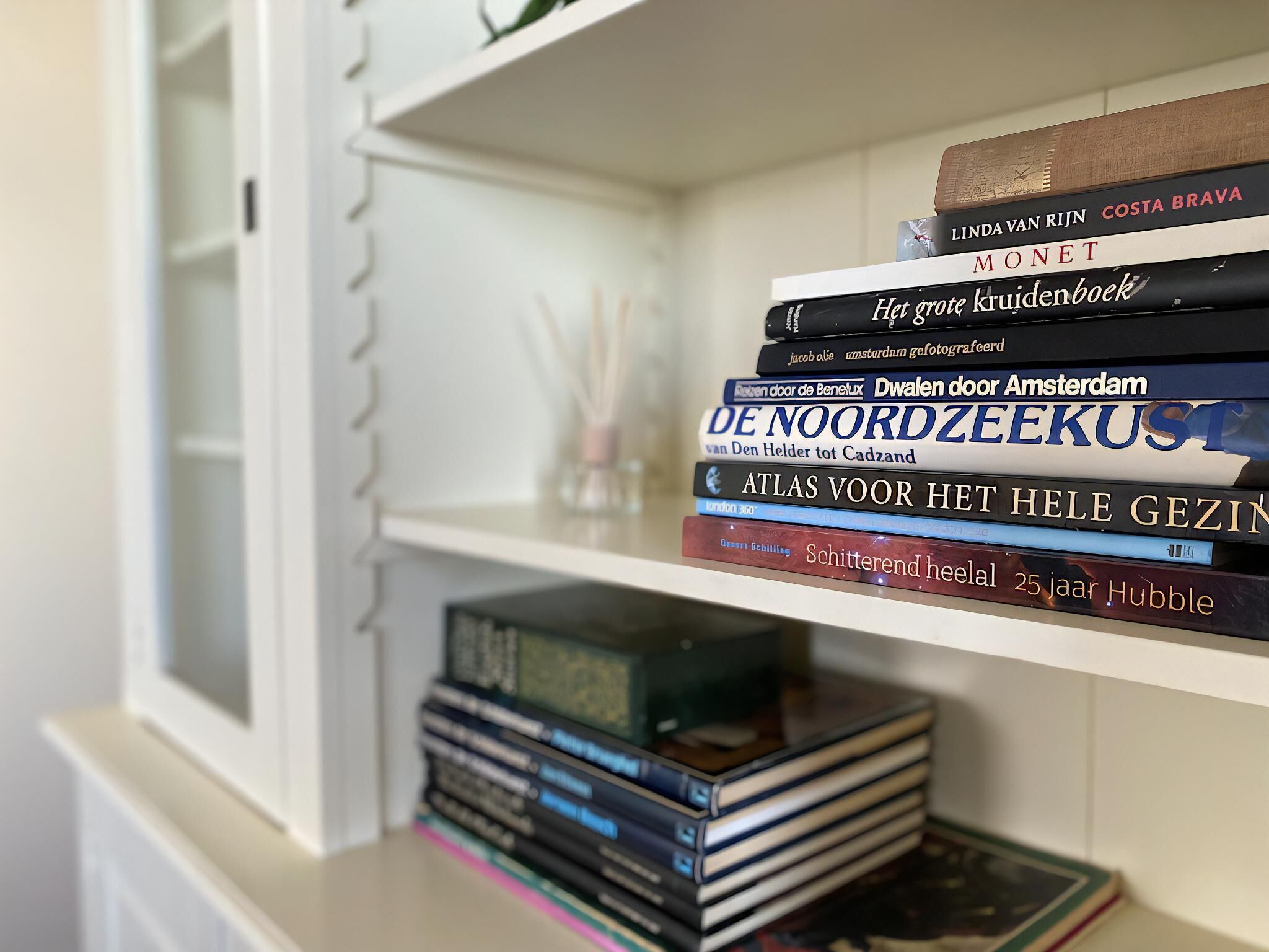Una estantería con una variedad de libros, incluyendo títulos como 'Het grote kruisboek' y 'Atlas voor het hele gezins'.