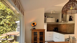 A modern kitchen with white cabinets, a wooden dining table, and a built-in oven.
