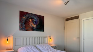 A bedroom with a white bed, two bedside lamps, a wall art piece, and a door. - Callantsoger Staete A210 (Callantsoog)