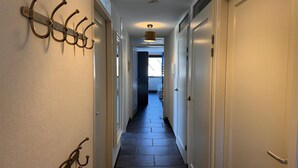 A hallway with a dark tiled floor, white walls, and a ceiling light fixture. - Callantsoger Staete A210 (Callantsoog)