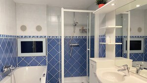 A modern bathroom with a freestanding bathtub, a glass-enclosed shower, and a vanity with a large mirror. - Callantsoger Staete A306 (Callantsoog)