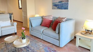 A living room with a grey sofa, a white armchair, a small table with a plant, and a painting on the wall. - Callantsoger Staete A306 (Callantsoog)