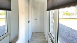 A narrow hallway with white walls, a door at the end, and large windows on both sides. - 3 bedroom accommodation in Callantsoog (Callantsoog)