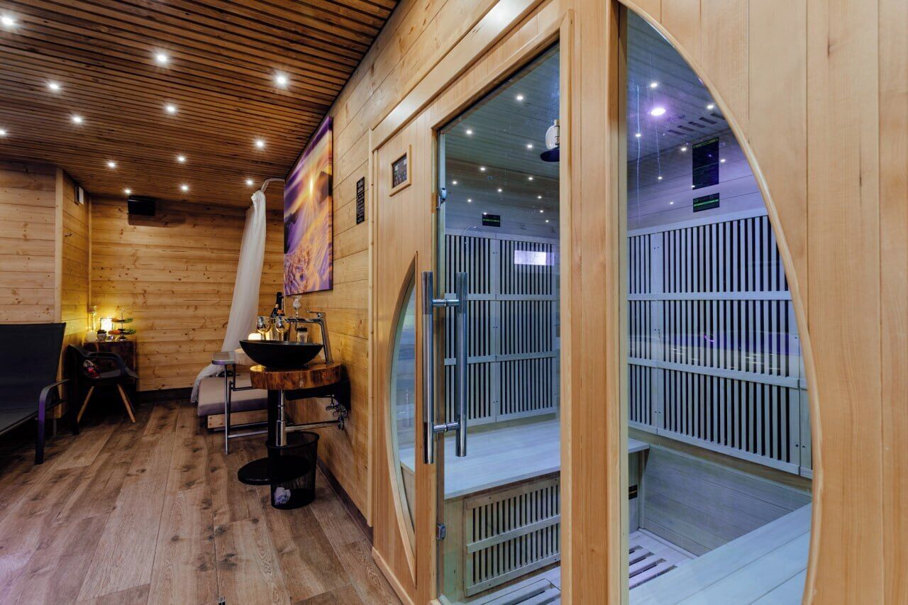 Un sauna avec des murs en bois, un banc, une table avec un lavabo et une porte en verre donnant sur une autre pièce.