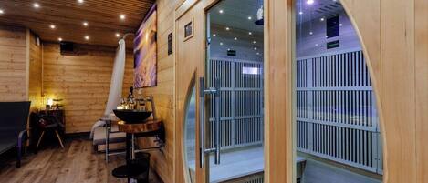 A sauna room with wooden walls, a bench, a table with a basin, and a glass door leading to another room.