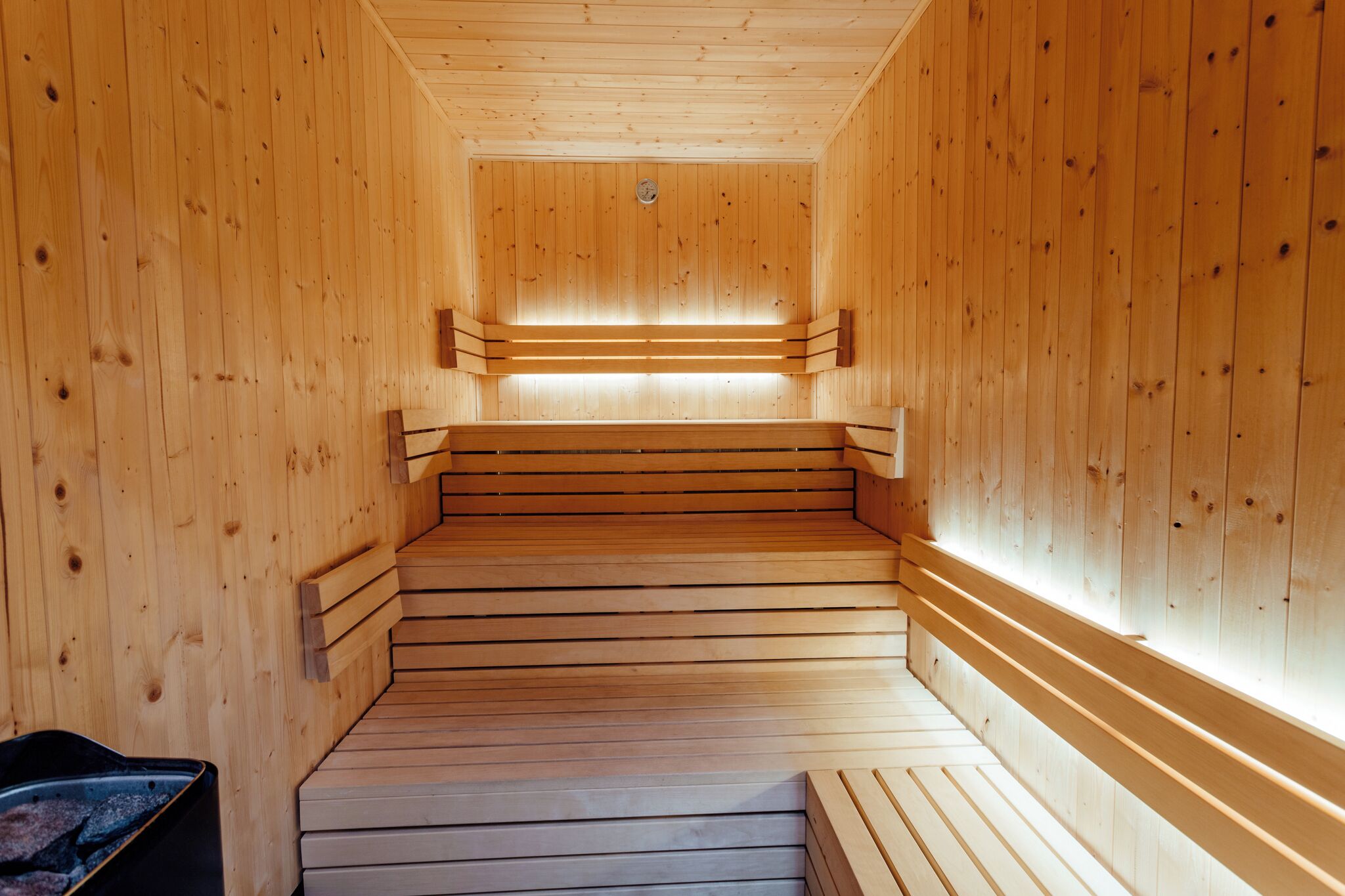 Uma sauna de madeira com bancos e um elemento de aquecimento central.
