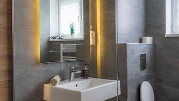 Een moderne badkamer met een wit wastafel, een spiegel en een toilet.