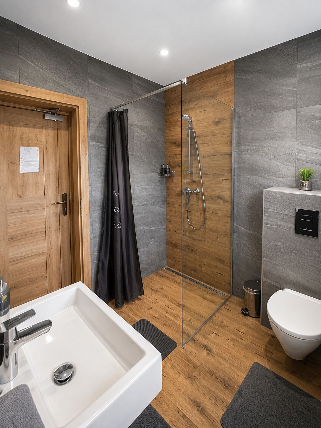 Een moderne badkamer met douche, toilet en wastafel.