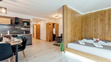 Ein modernes, kompaktes Wohnzimmer mit Küche, Essbereich und Schlafzimmer.