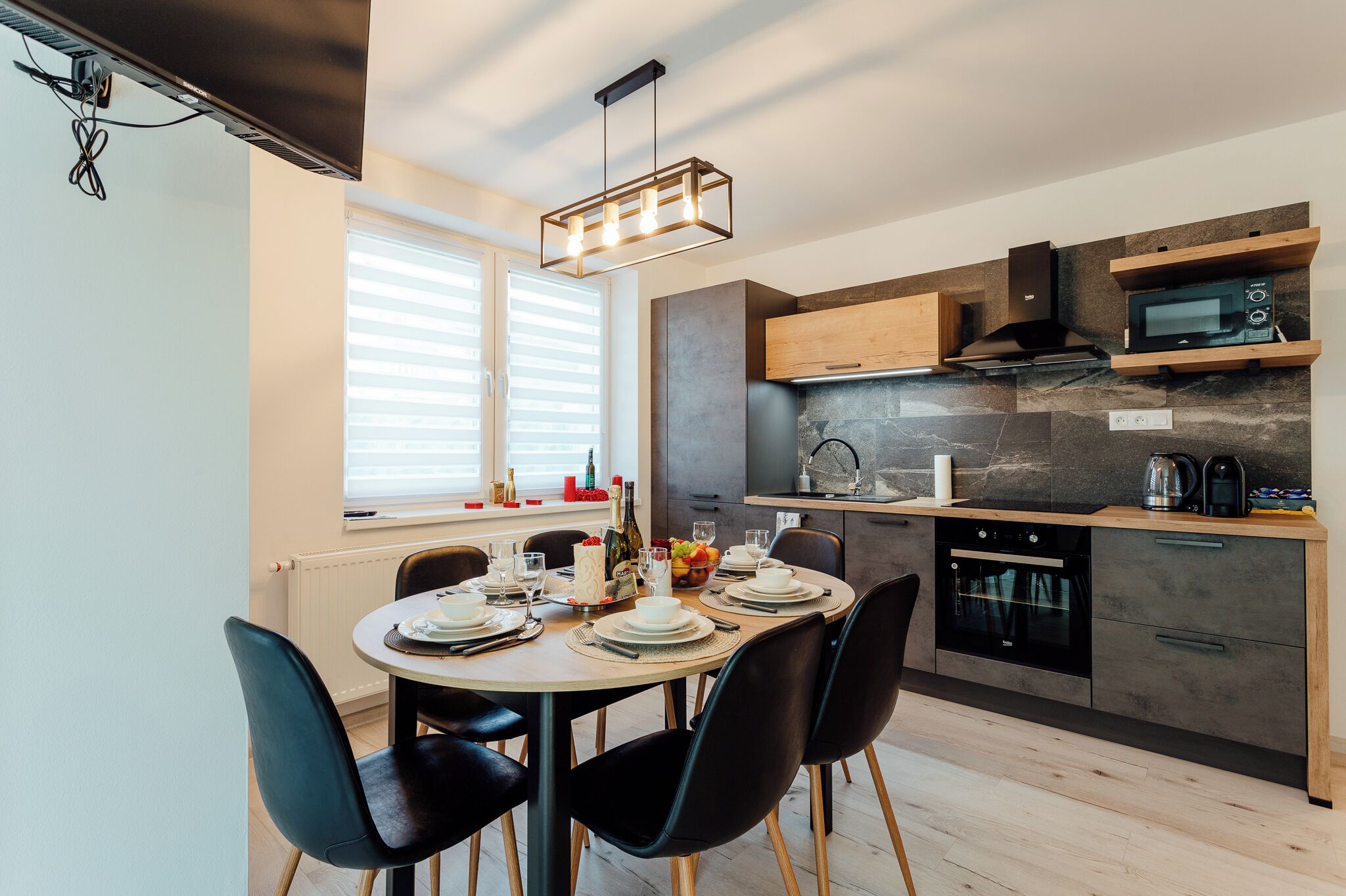 Una cocina moderna con zona de comedor. Incluye estufa, microondas y armarios de madera.