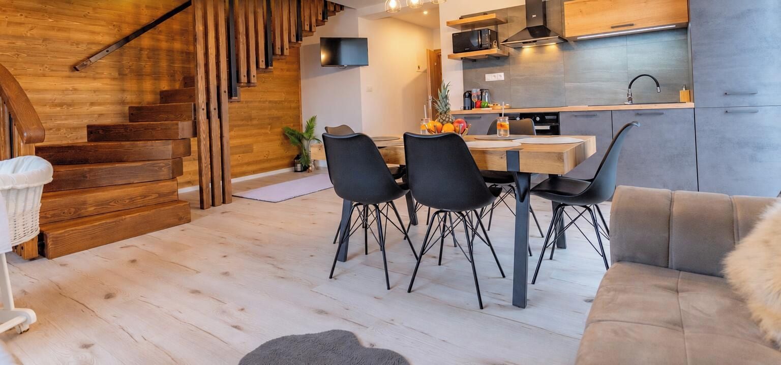 Eine moderne Küche mit Essbereich, einer Holztreppe und einer Couch.