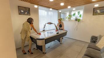 Een kamer met een pooltafel, een bank en een raam met planten.