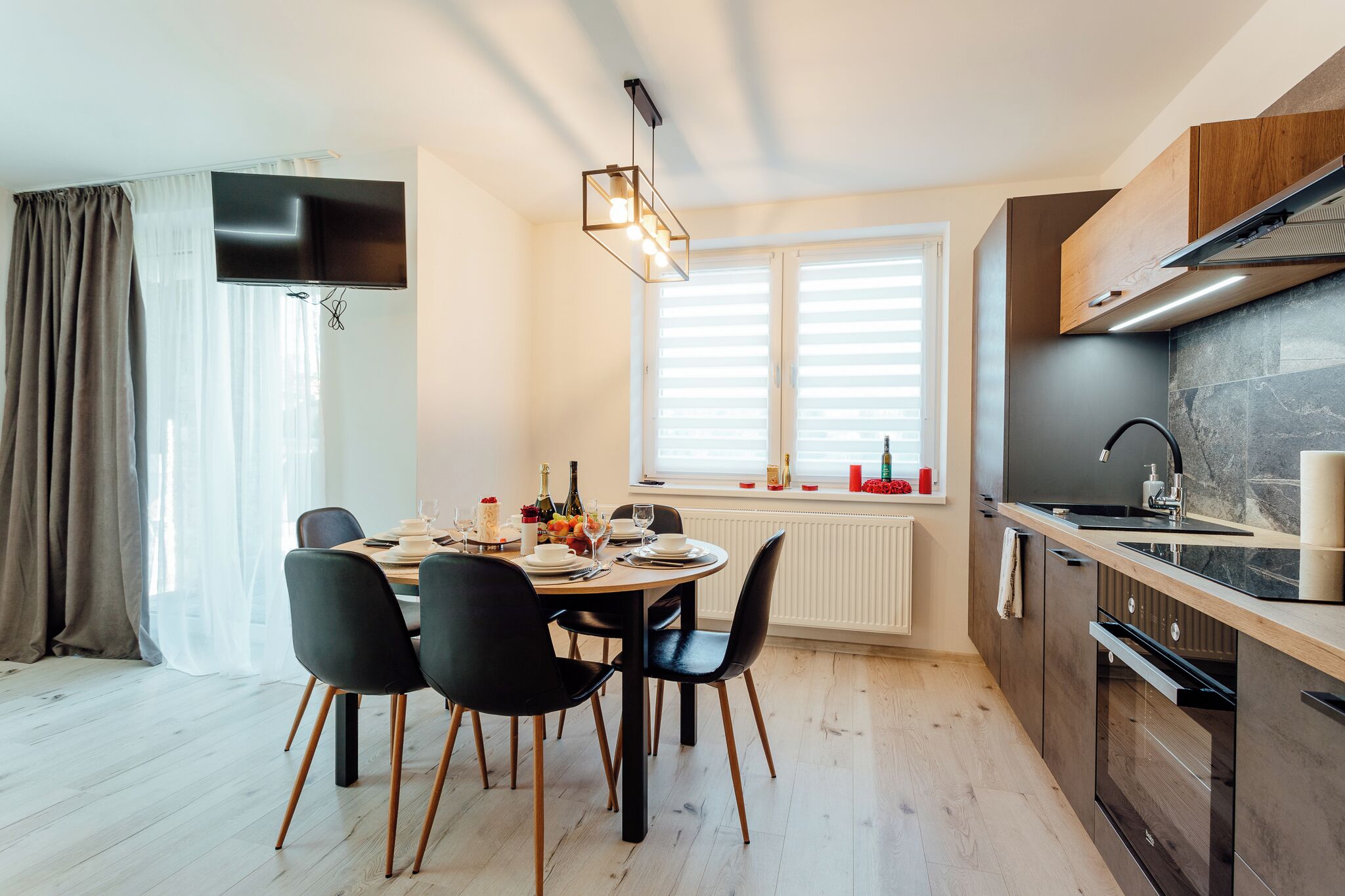 Una cocina moderna con comedor, que incluye un ventanal grande, electrodomésticos integrados y una mesa de comedor con sillas.